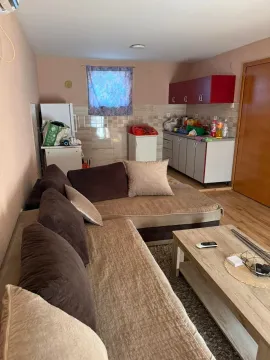 Living room with a sectional sofa and a small kitchen in the background. - image 3