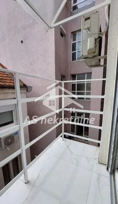 Manji balkon sa belom ogradom i keramičkim pločicama.