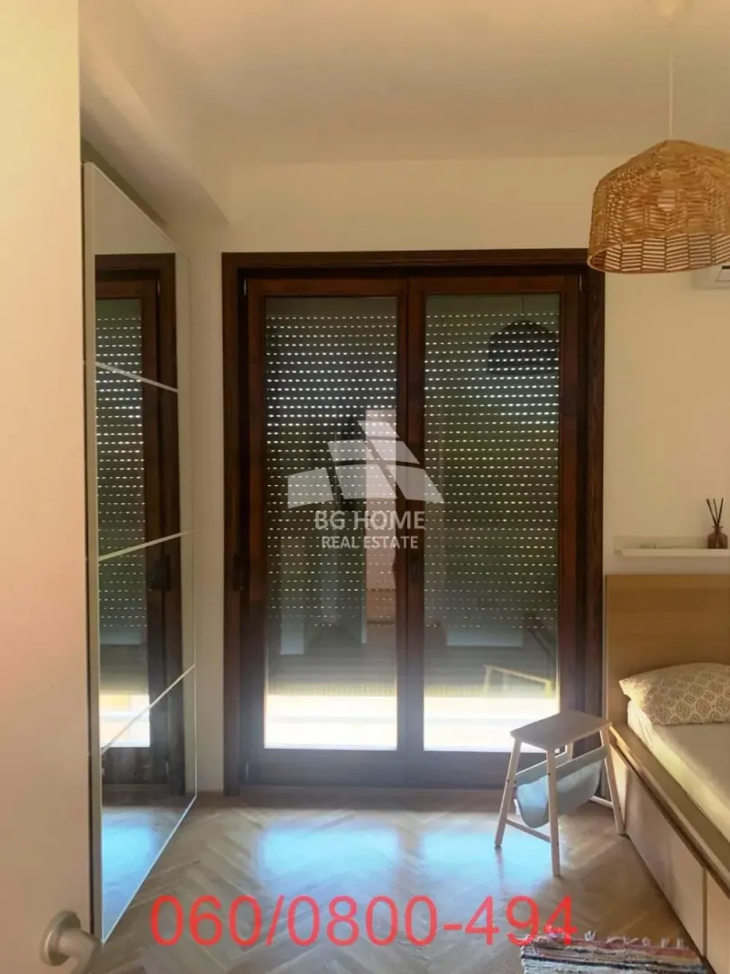 Nameštena spavaća soba sa krevetom, ugradnim ormanom i balkonskim vratima.