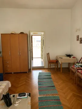 Dnevna soba sa drvenim ormarom, stolom i izlazom na terasu. - image 3