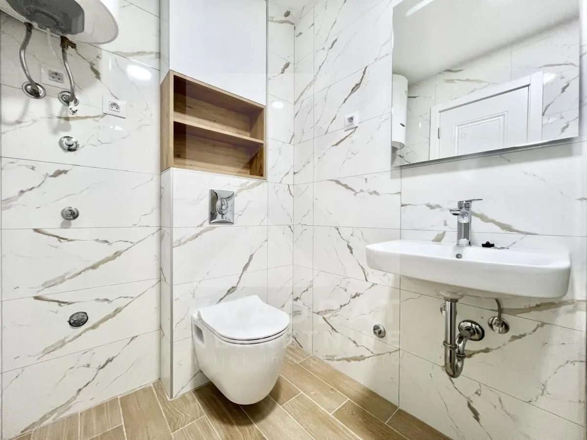 Moderne kupatilo sa tuš kabinom, umivaonikom i ugradnom wc šoljom.