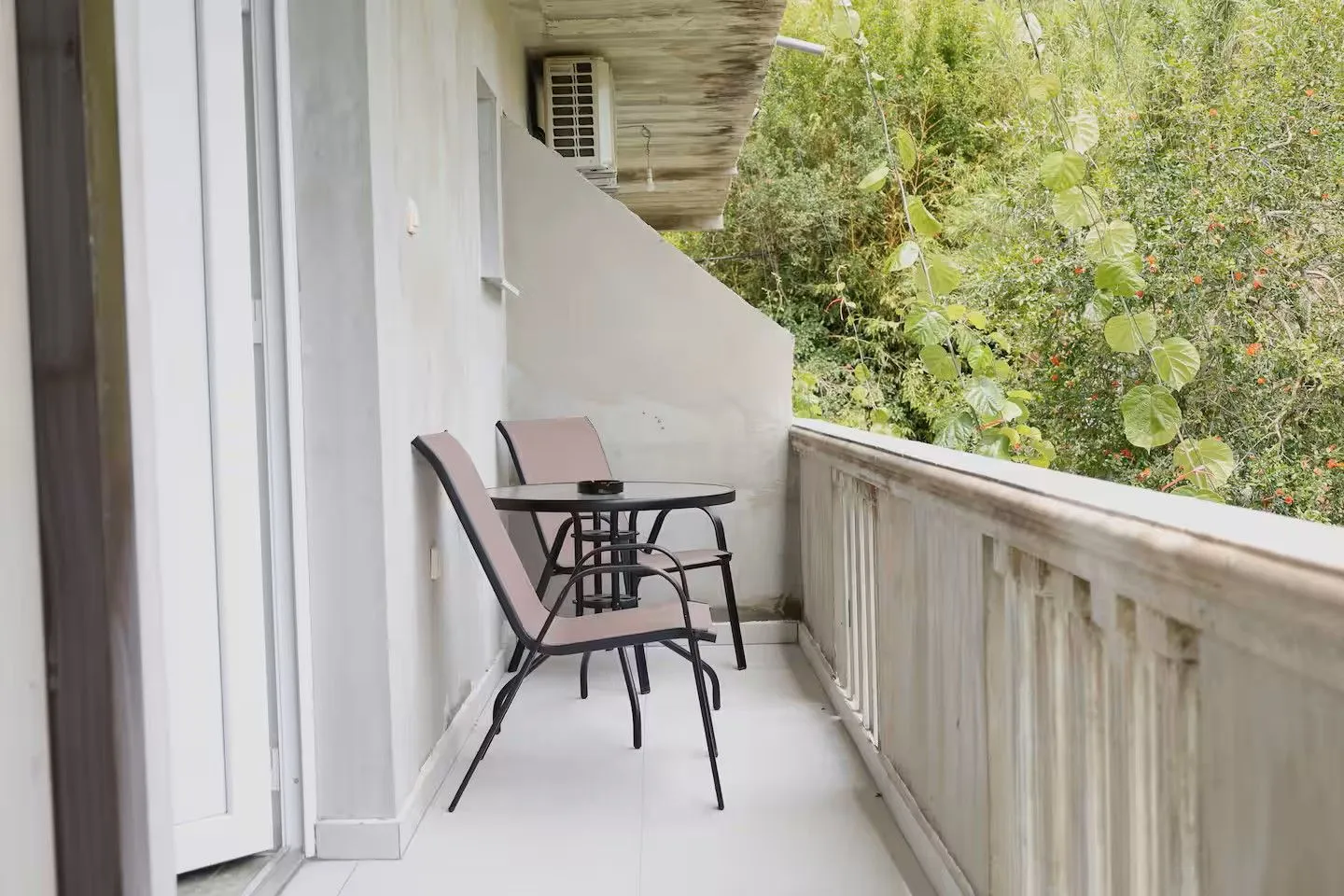 Manji namješteni balkon sa stolom i dvije stolice i pogledom na zelenilo.