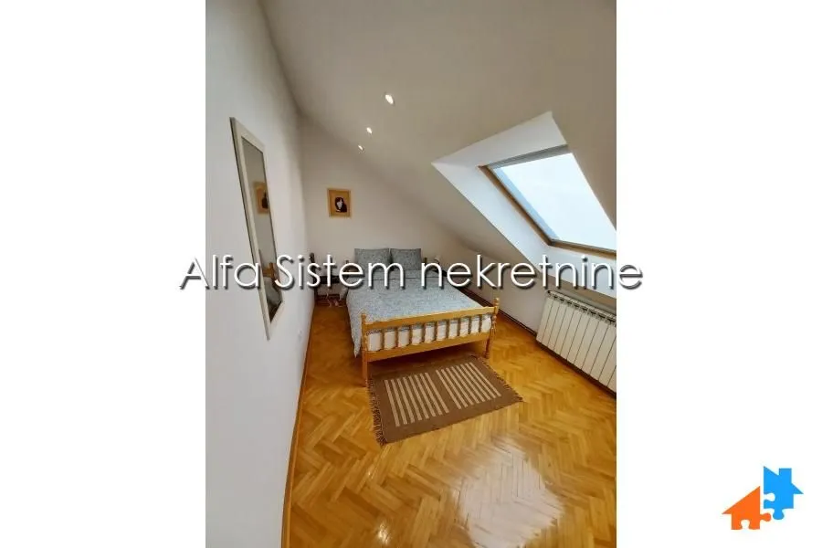 Attic bedroom with a bed, skylight, and wooden floor.