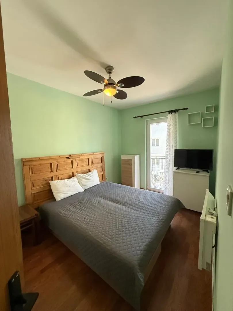 Bedroom with a double bed, wooden headboard, ceiling fan, and access to the terrace.