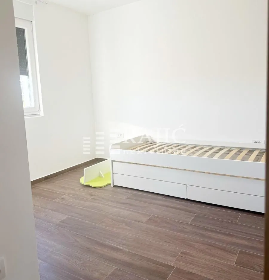 Bright bedroom with a bed and wooden flooring.