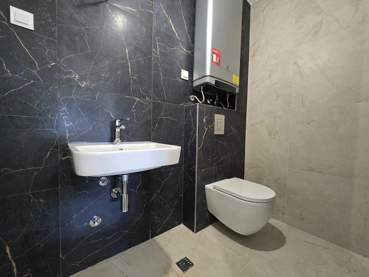 Modern bathroom equipped with a sink, wall-hung toilet, and water heater.