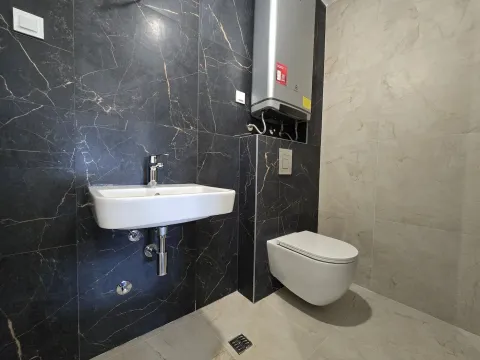 Modern bathroom equipped with a sink, wall-hung toilet, and water heater. - image 8