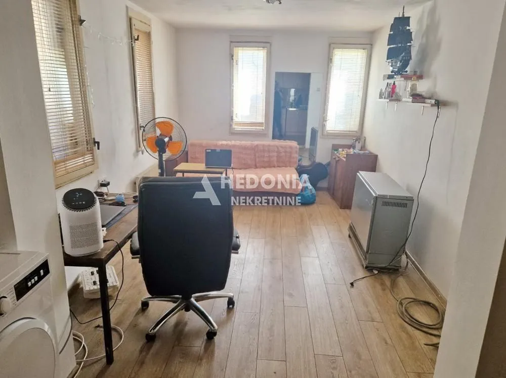 Dnevna soba sa radnim stolom, kaučem i prozorima.