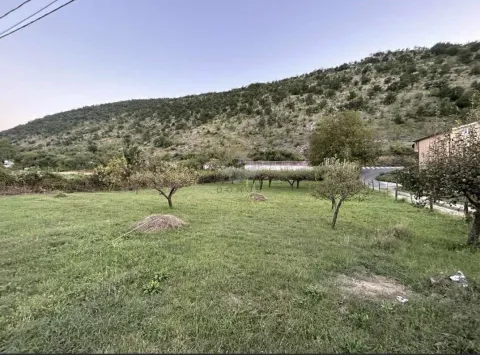 Zeleni travnati plac okružen prirodom i brdima. - image 4