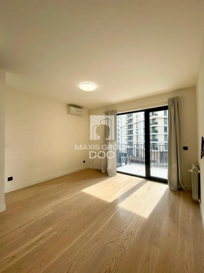 Empty room with wooden flooring and access to a balcony.
