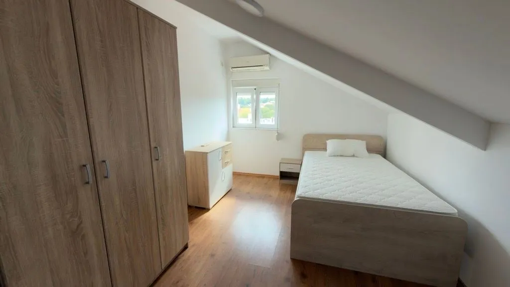 Attic bedroom with a bed and a wooden wardrobe.