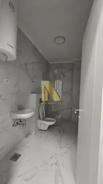 Moderno kupatilo sa svetlim mermernim pločicama, umivaonikom i WC šoljom. - image 11