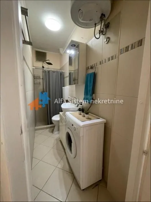 Smaller bathroom with a shower cabin, washbasin, and washing machine.