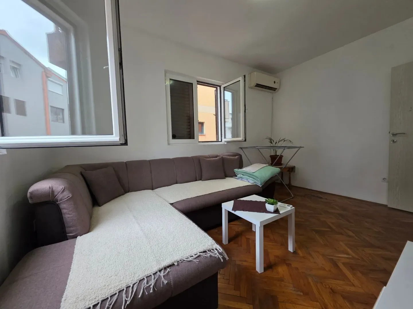 Living room with a corner sofa, coffee table, and parquet flooring.