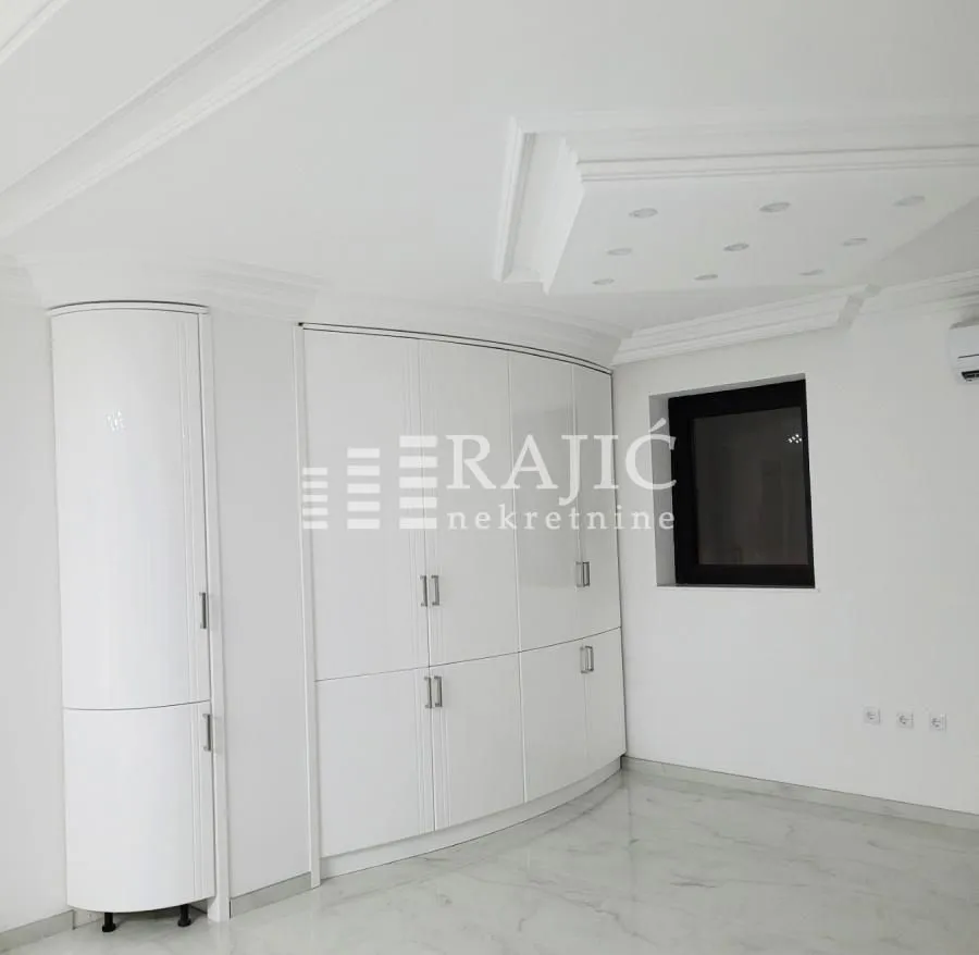 White bedroom with built-in wardrobe and decorative dropped ceiling.