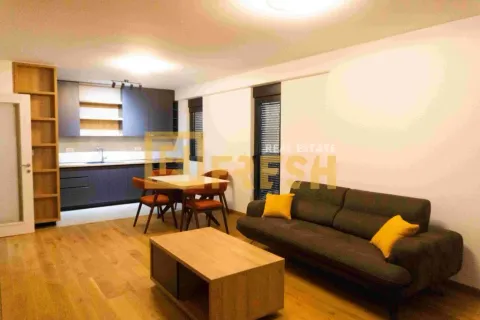 Living room with sofa, coffee table, dining area, and kitchen in the background. - image 6