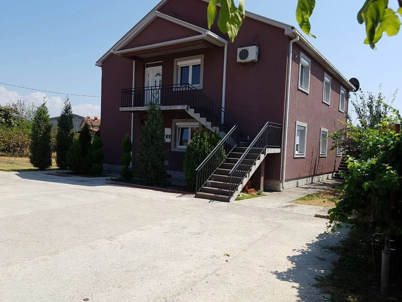 Spoljašnji izgled dvospratne kuće sa spoljnim stepeništem i dvorištem.
