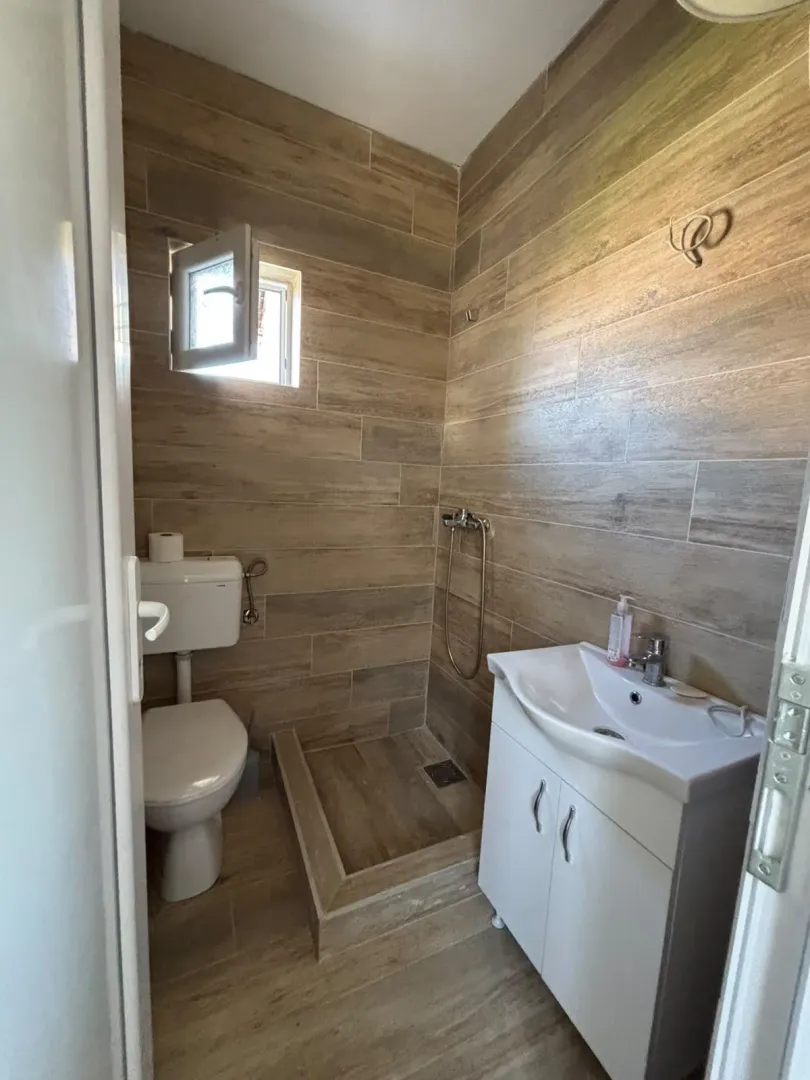 Small bathroom tiled with wood-effect ceramic tiles featuring a walk-in shower.