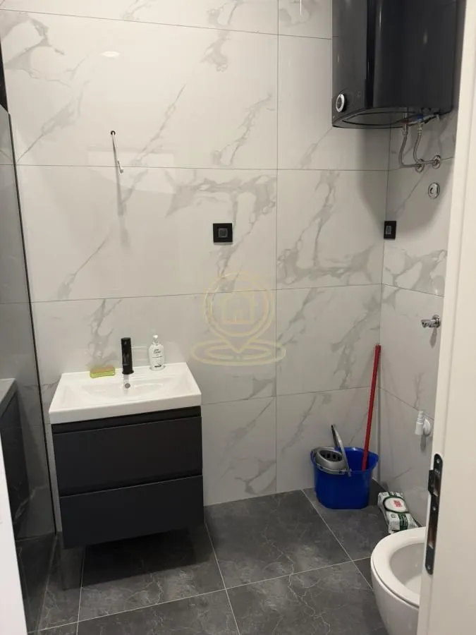 Moderno kupatilo sa umivaonikom, WC šoljom i bojlerom na zidu.