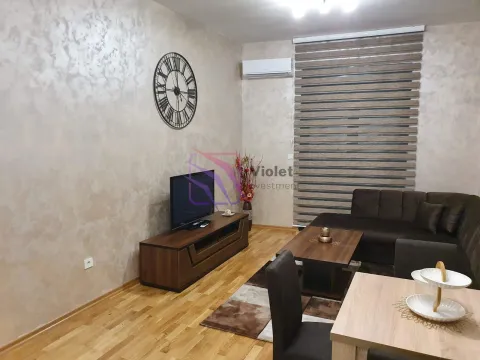 Living room furnished with a sofa, TV unit, and dining table. - image 2