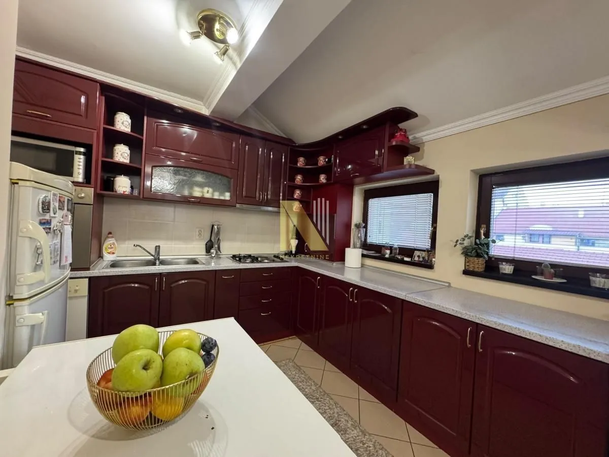 Kuhinja sa tamnim drvenim elementima i radnim delom.