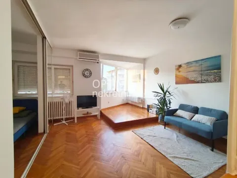 Dnevna soba sa drvenim podom, plavom sofom i TV-om. - image 3
