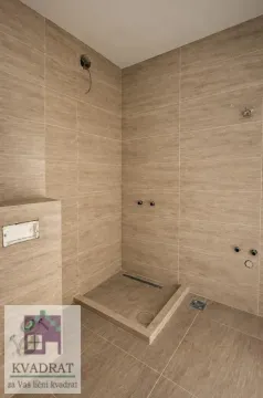Nekorišćeno kupatilo obloženo keramičkim pločicama u bež tonovima. - image 6