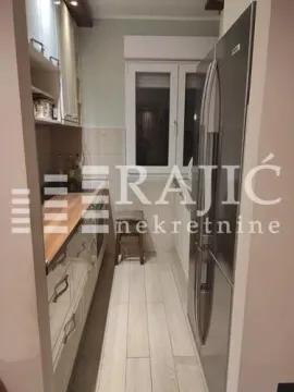 Small equipped kitchen with white cabinets and a large refrigerator. - image 5