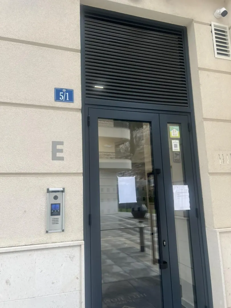 Entrance to a residential building with a modern intercom and glass door.