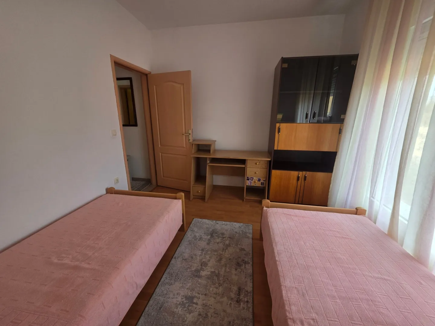 Bedroom with two single beds, a desk, and a wardrobe.