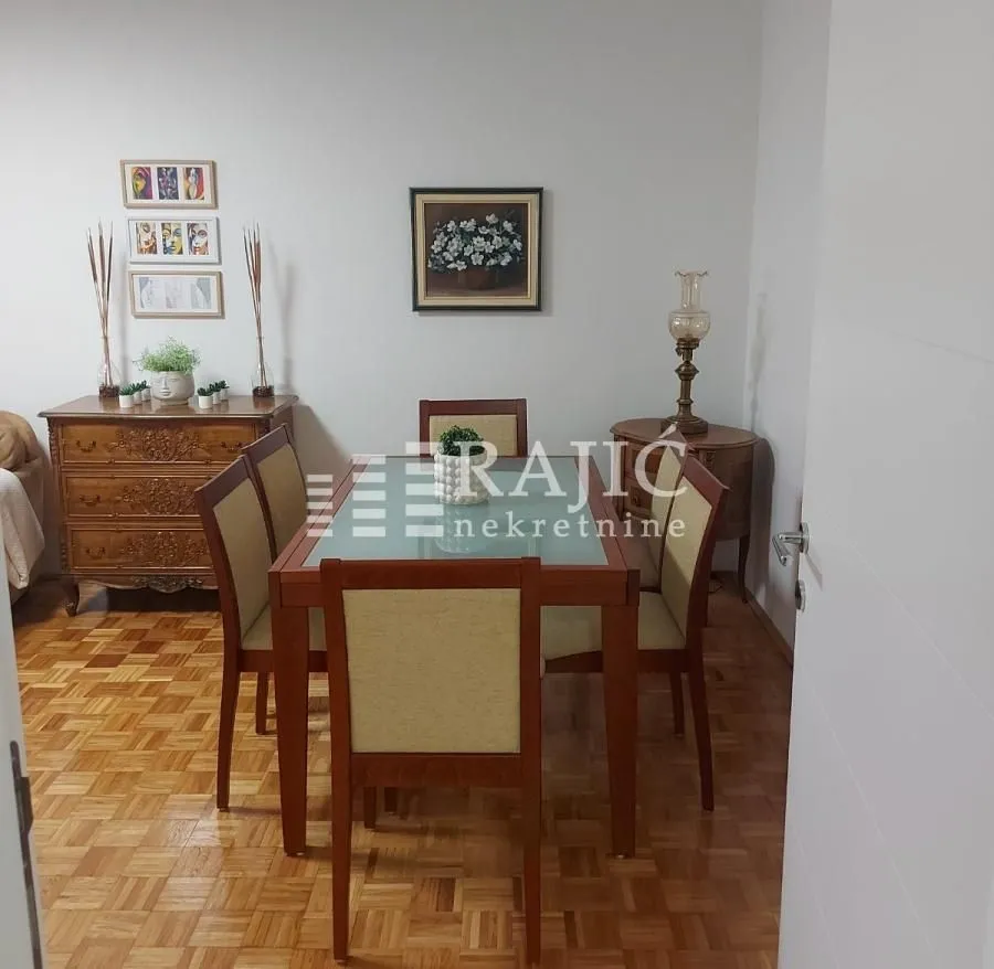 Dining room with a wooden table, chairs, and a chest of drawers.