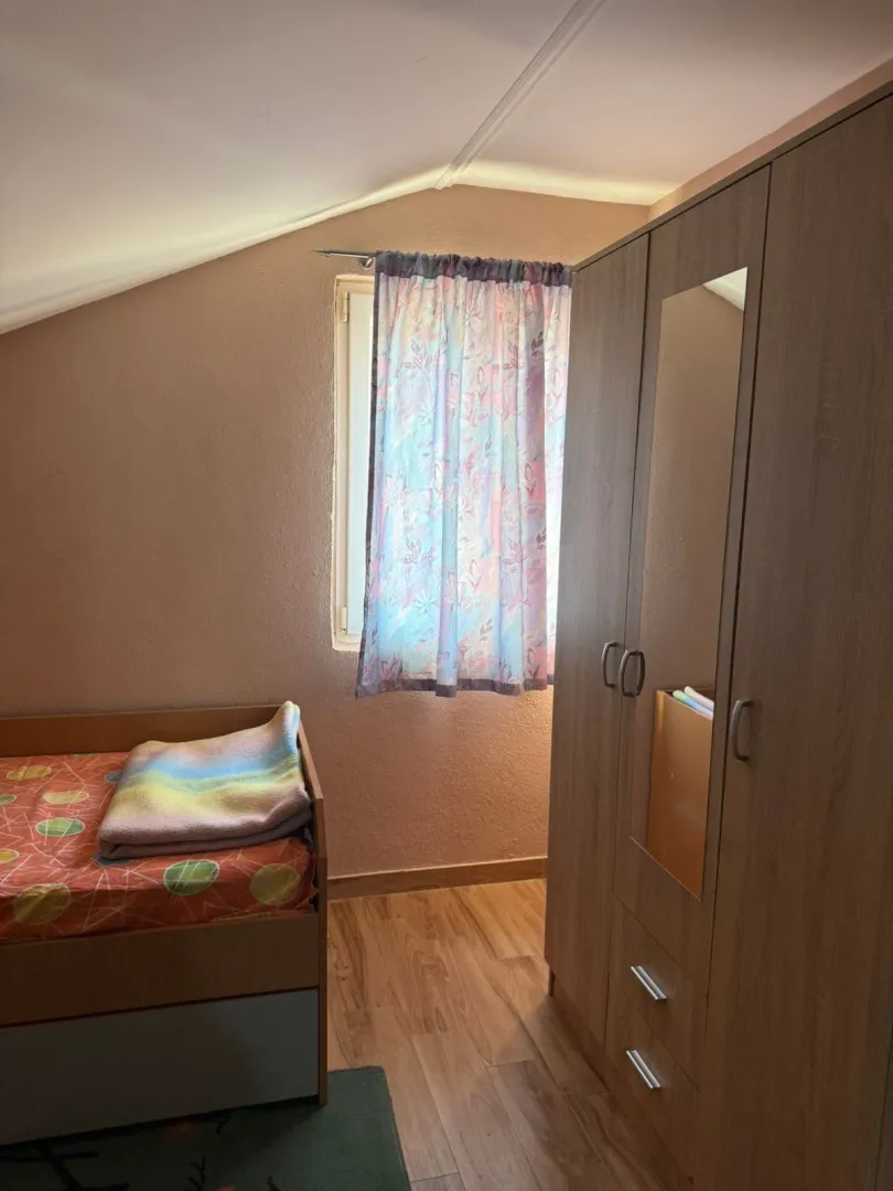 Small bedroom with a bed, wardrobe, and a window.
