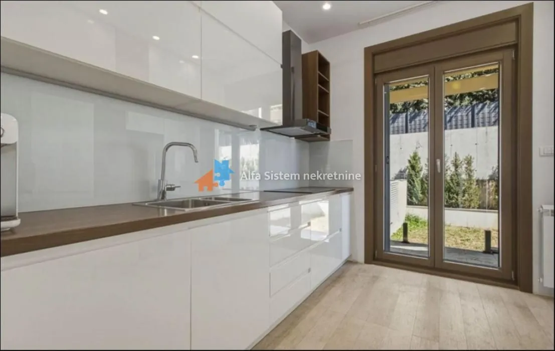 Modern white kitchen with a sink and a view of the yard.