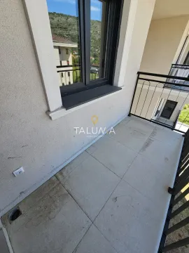 Pogled na popločani balkon sa crnom ogradom i prozorom. - image 5