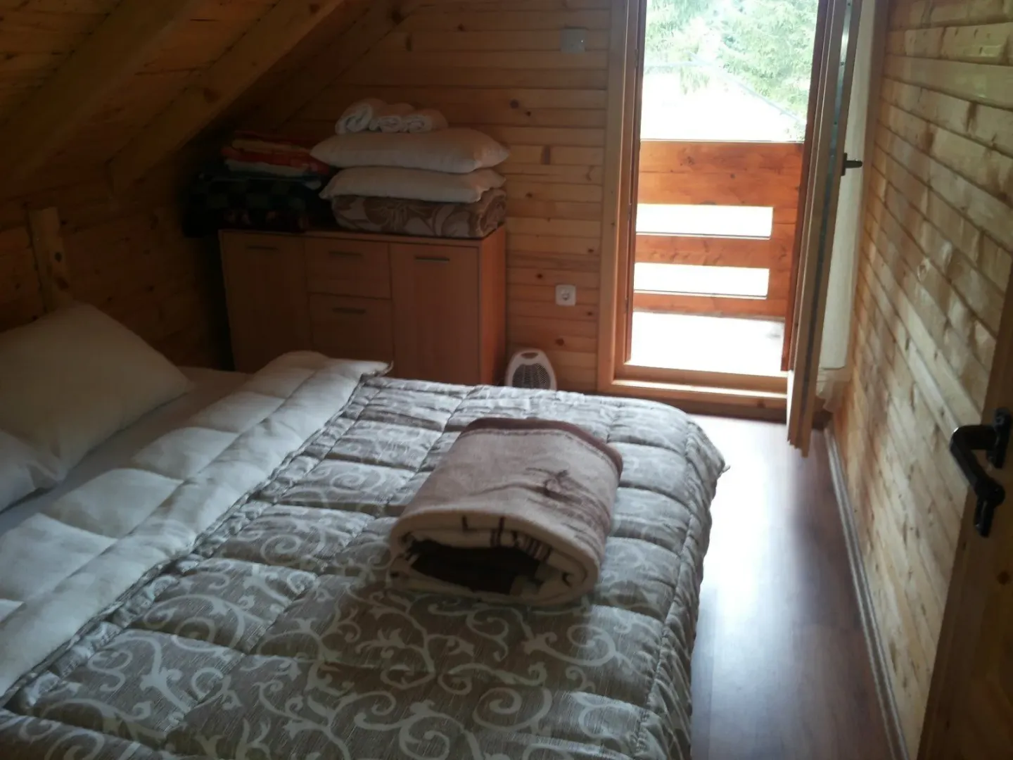 Spavaća soba u drvenoj kući sa izlazom na balkon.