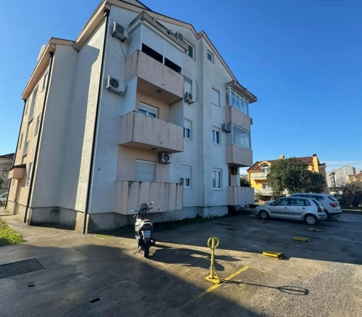 Exterior view of a residential building with an adjacent parking area.