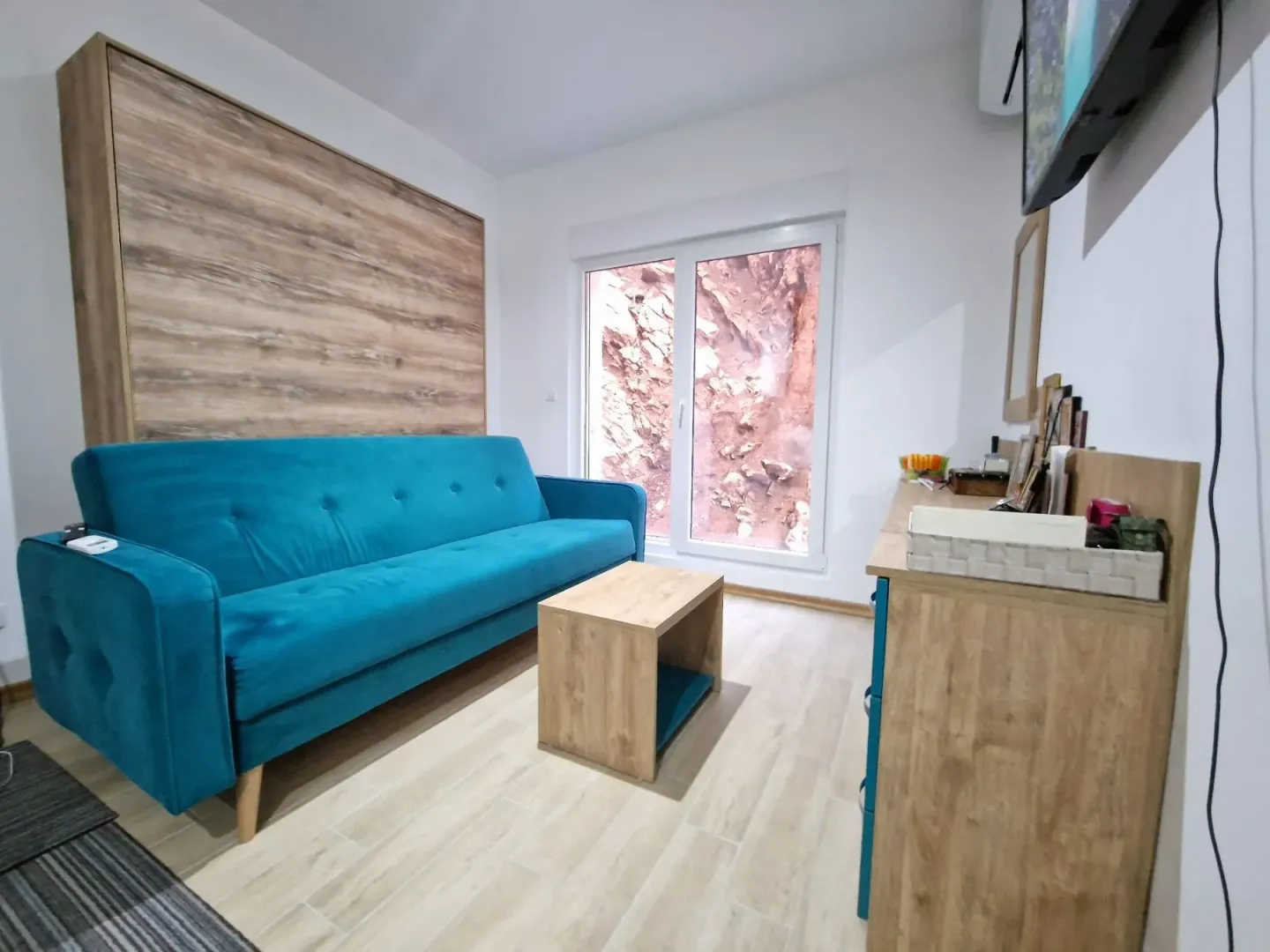 Living room with a blue sofa, wooden coffee table, and dresser.