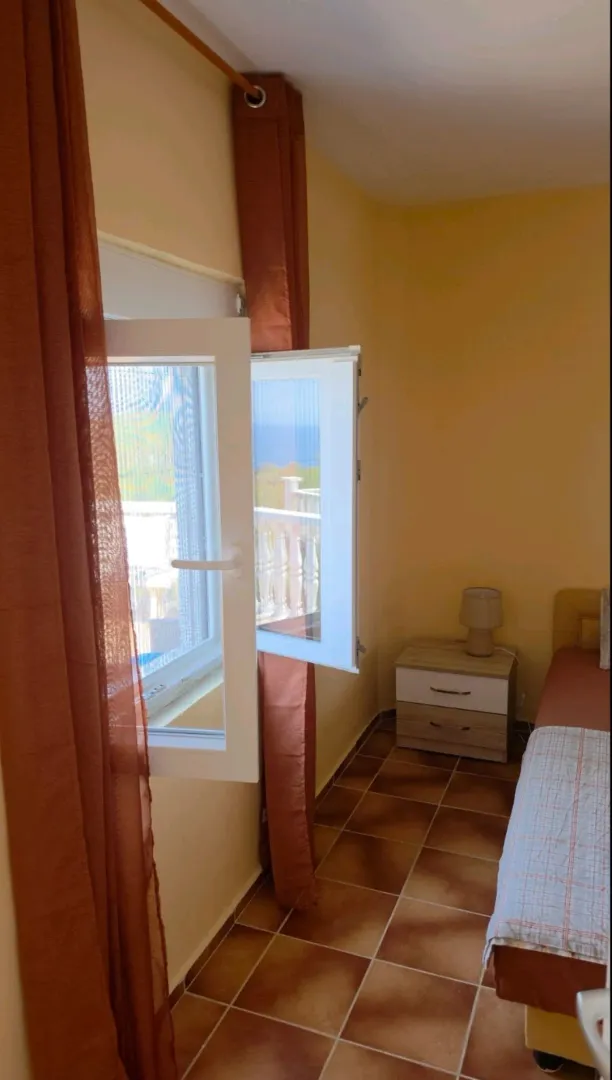 Small bedroom with a bed, nightstand, and a window with a view.
