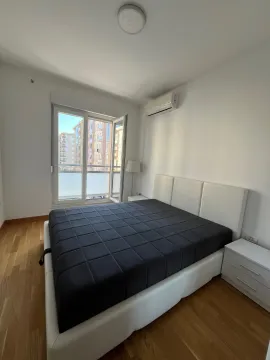 Bright bedroom with a double bed, white nightstands, and balcony doors. - image 6