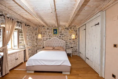 Rustic bedroom with a stone wall, wooden ceiling, and a double bed. - image 7