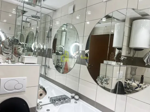 Savremeno opremljeno kupatilo sa kadom, velikim ogledalima i keramičkim pločicama. - image 5