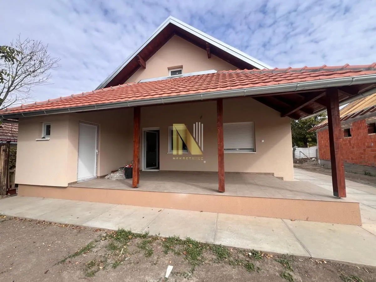 Prednji pogled na spratnu kuću sa natkrivenom terasom i krovom od crepa.