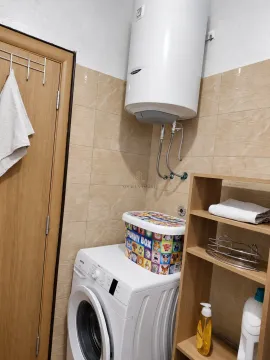 Bathroom with a washing machine, water heater, and a wooden shelf. - image 9