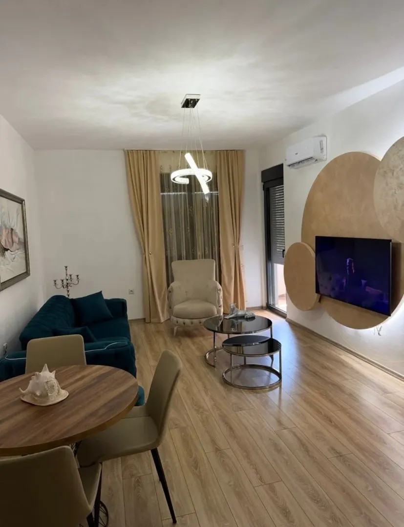 Moderan i svijetao dnevni boravak sa garniturom, trpezarijskim stolom i TV-om.