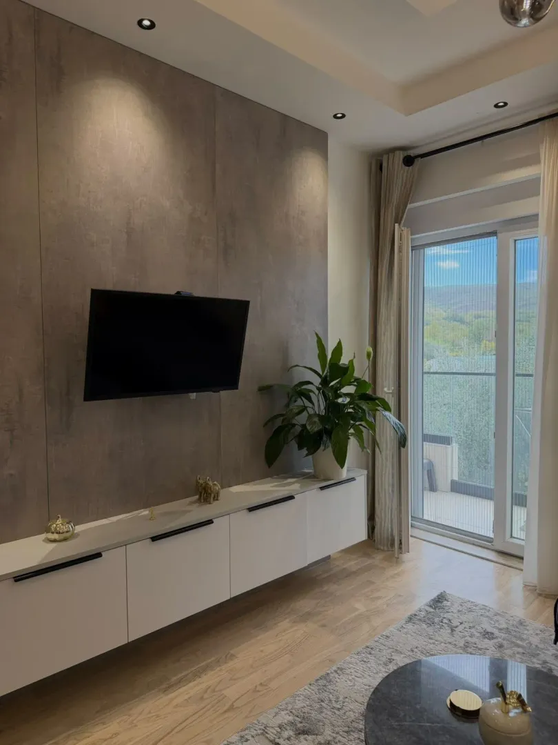 Modern living room with a TV wall unit, white console, and access to the terrace.