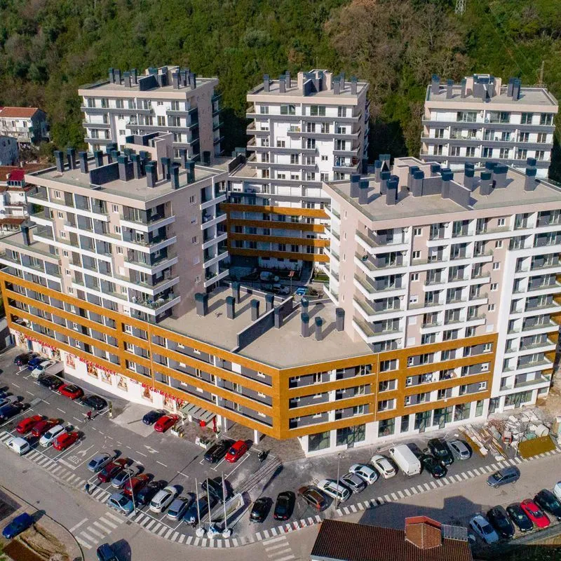 Pogled iz vazduha na stambeni kompleks sa parkingom i okruženjem.