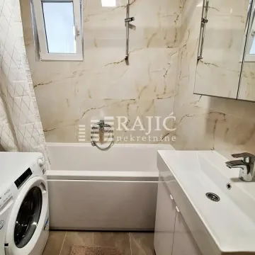 Modern bathroom with a bathtub, sink, and washing machine. - image 8