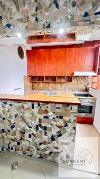 Small kitchen with wooden cabinetry and a mosaic-tiled bar counter. - image 14