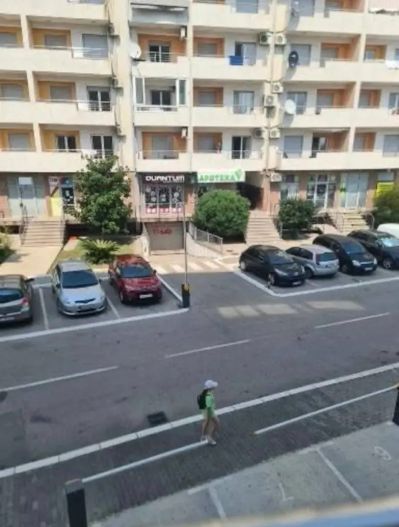 Pogled sa prozora na ulicu, parking i stambenu zgradu preko puta.