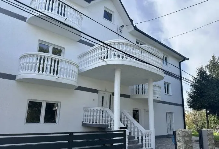 Spoljašnji izgled višespratne kuće sa belim terasama i balustradama.